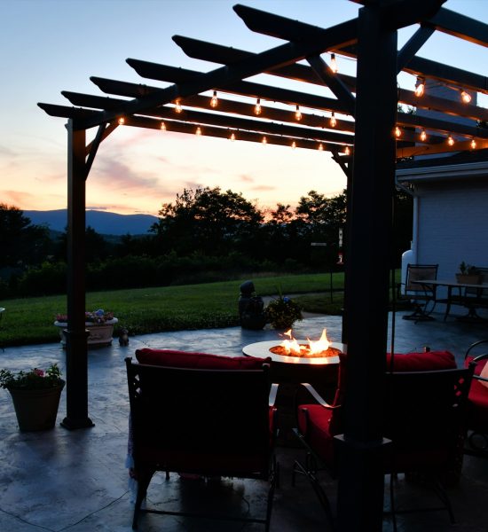 Comfortable outside seating area with fire pit table and pergola with lights in evening or morning